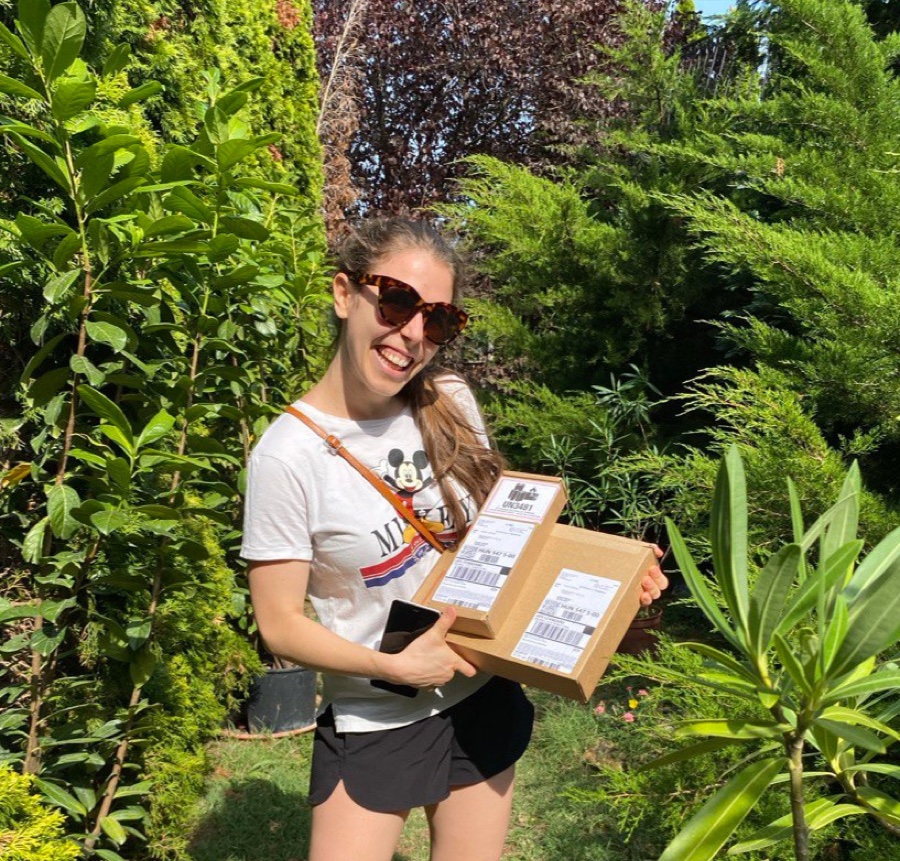 Dia Hidvégi smiling in a garden, holding a parcel
